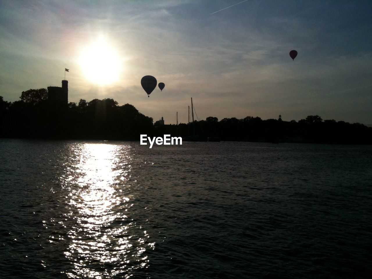 Silhouette hot air balloons in mid-air against sky during sunset