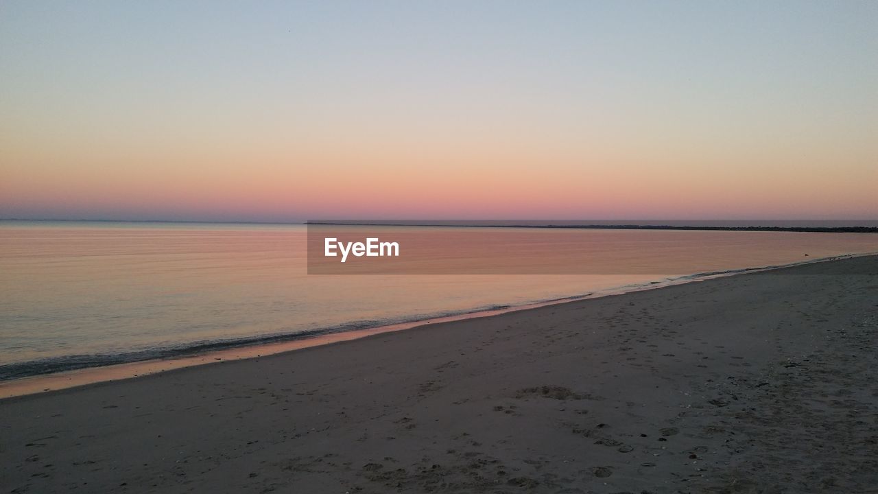 SCENIC VIEW OF SEA AGAINST CLEAR SKY DURING SUNSET