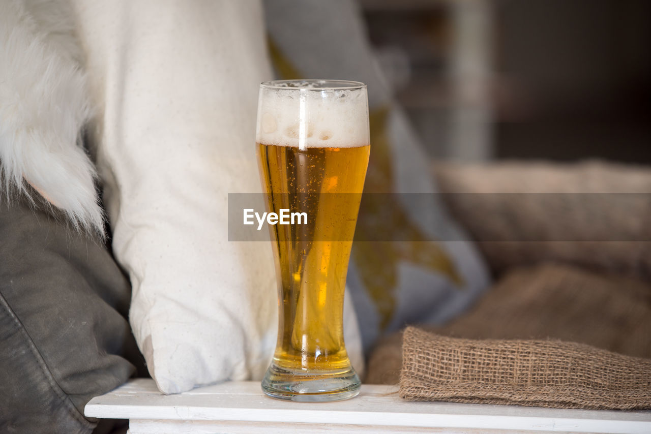 CLOSE-UP OF BEER GLASS ON TABLE WITH ICE