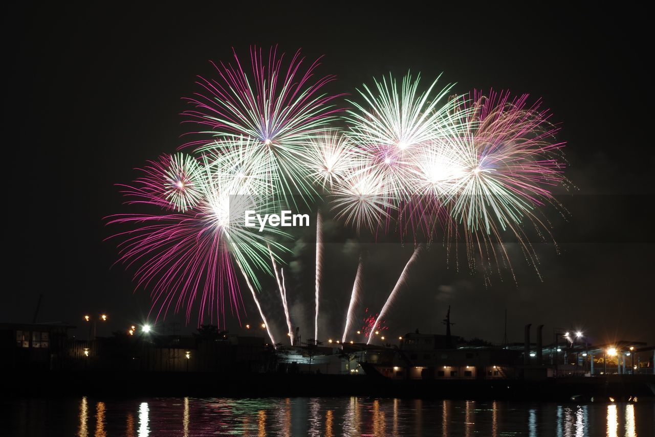 FIREWORK DISPLAY OVER RIVER AT NIGHT