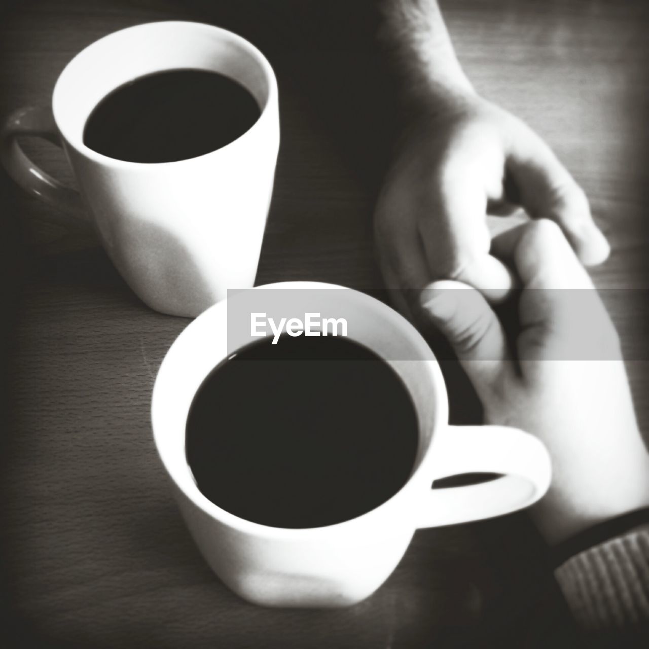 Cropped hand of couple with coffee on table
