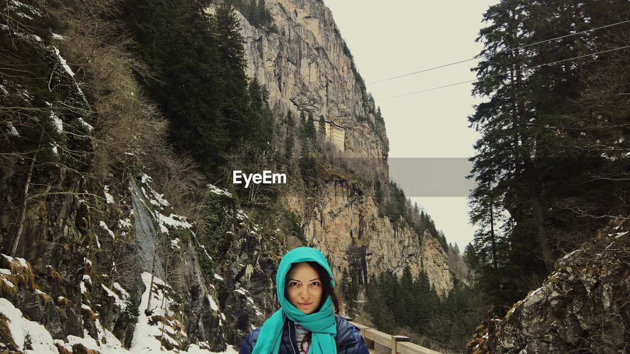 Woman in warm clothes standing against mountain