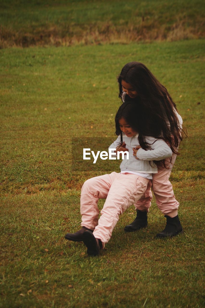 Playful siblings on field at park