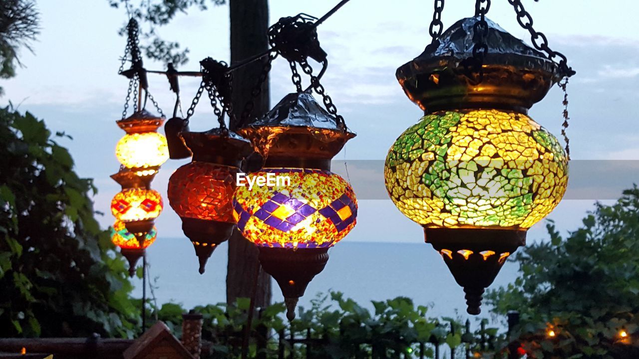 LOW ANGLE VIEW OF MULTI COLORED LANTERNS HANGING FROM TREE