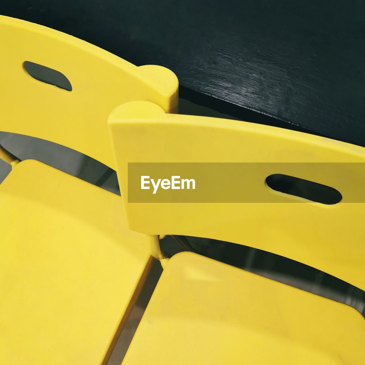 HIGH ANGLE VIEW OF EMPTY CHAIRS AND TABLE AGAINST YELLOW WALL