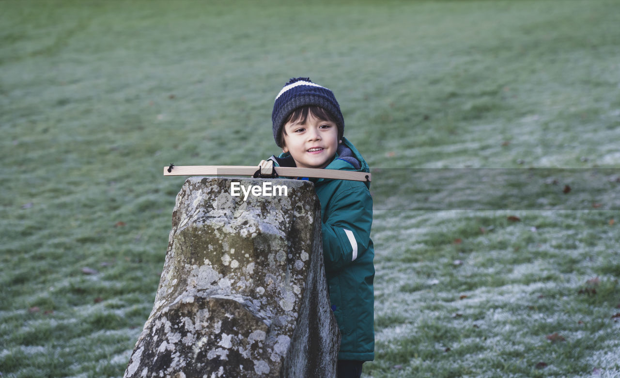 Smiling boy holding toy on built structure in park