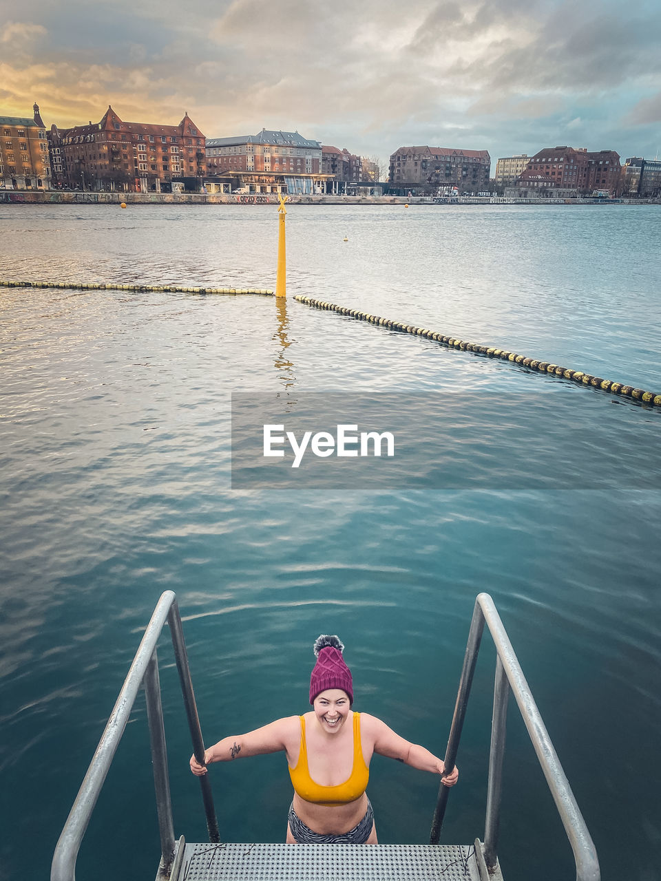 Happy winter bather at sunrise getting in water in copenhagen, denmark