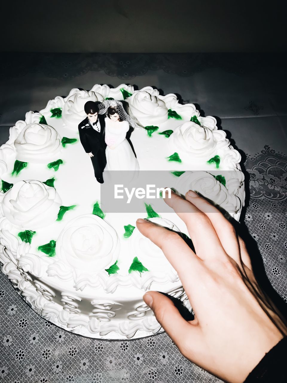 Cropped hand of bride touching wedding cake on table