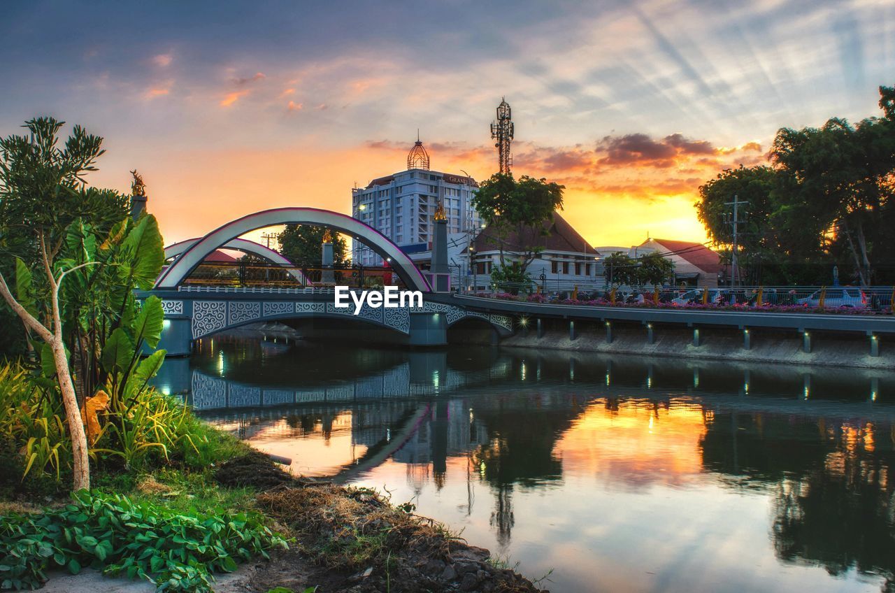 BRIDGE OVER RIVER AGAINST SKY DURING SUNSET