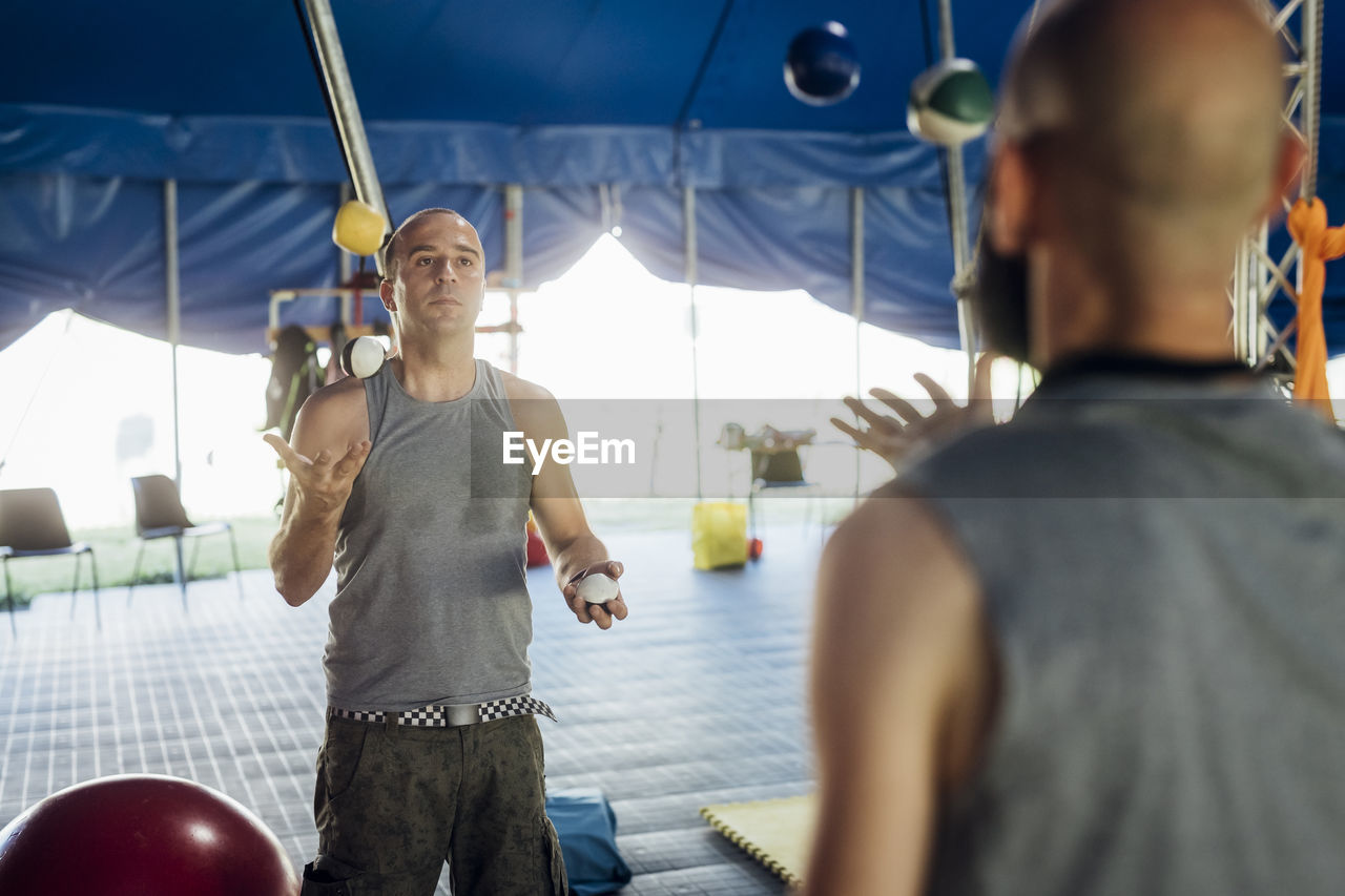 Male acrobats practicing while juggling balls in circus