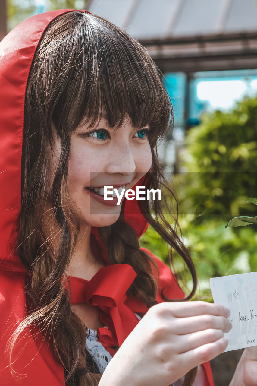 PORTRAIT OF A SMILING GIRL HOLDING CAMERA