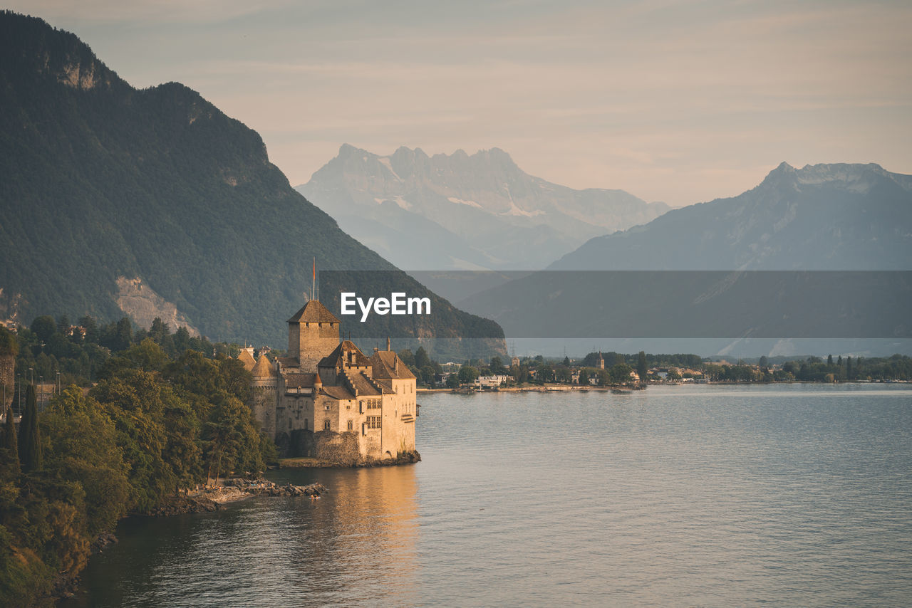 SCENIC VIEW OF LAKE BY BUILDINGS AGAINST MOUNTAIN