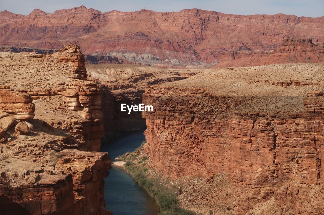 Landscape of steep cliffs and the colorado river between with pink mountains in the background