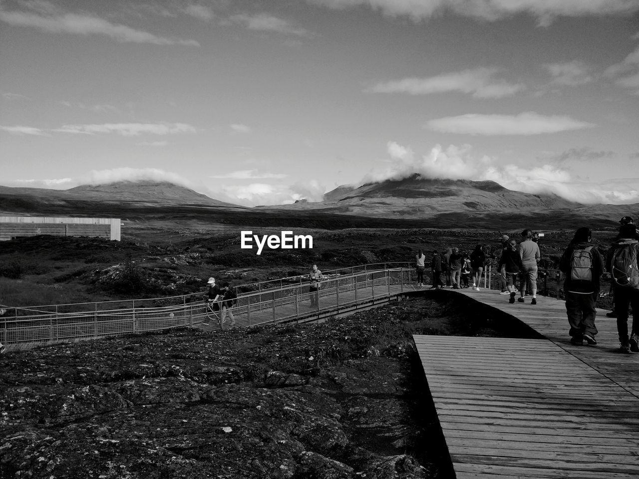 GROUP OF PEOPLE WALKING ON MOUNTAIN ROAD AGAINST SKY