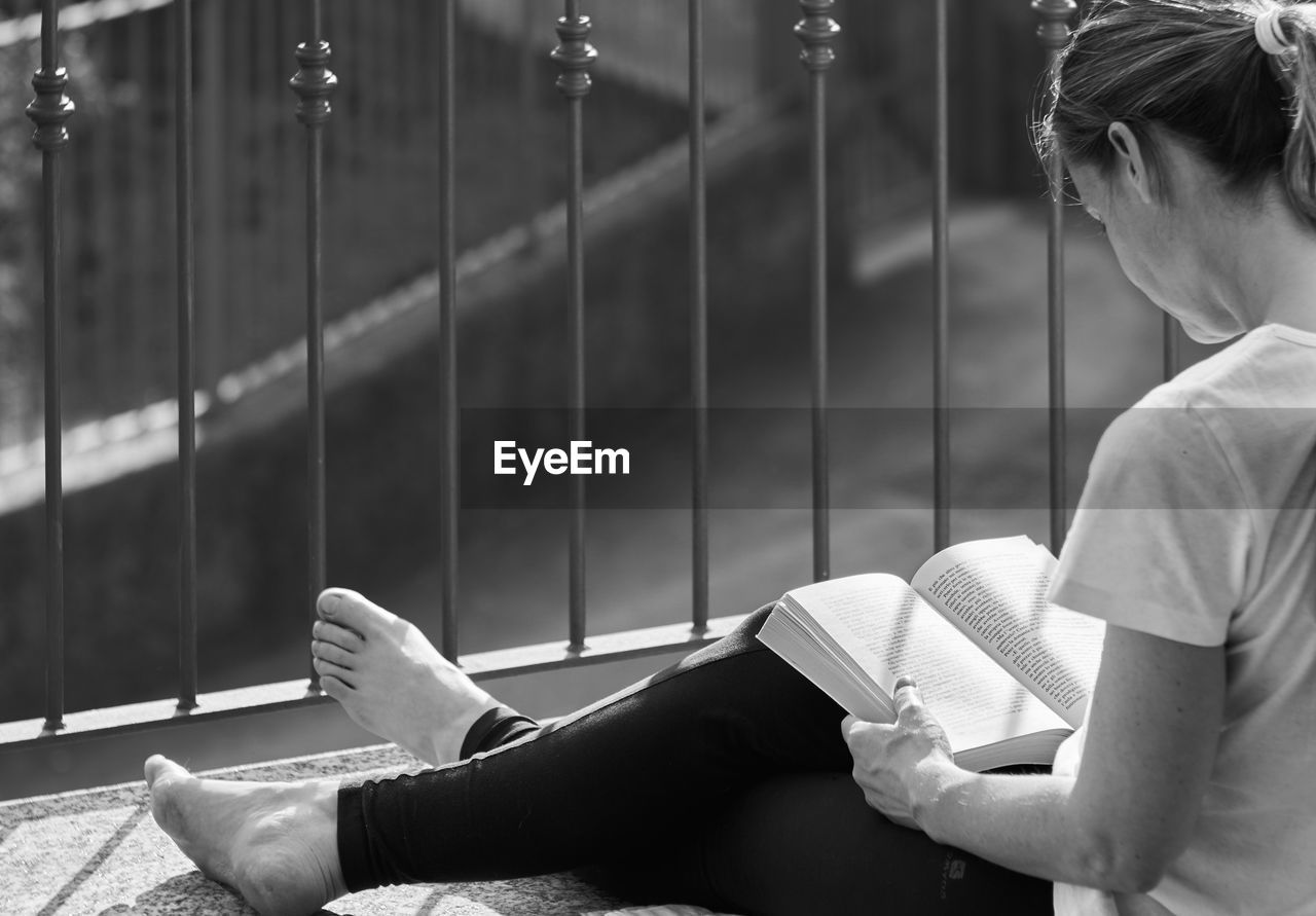 YOUNG WOMAN SITTING ON BOOK