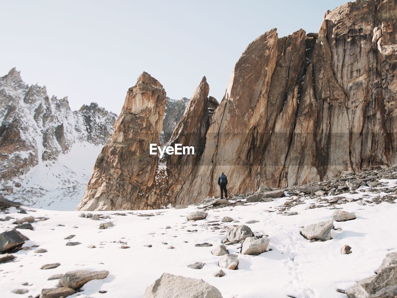 Rear view of man standing against rock formations during winter