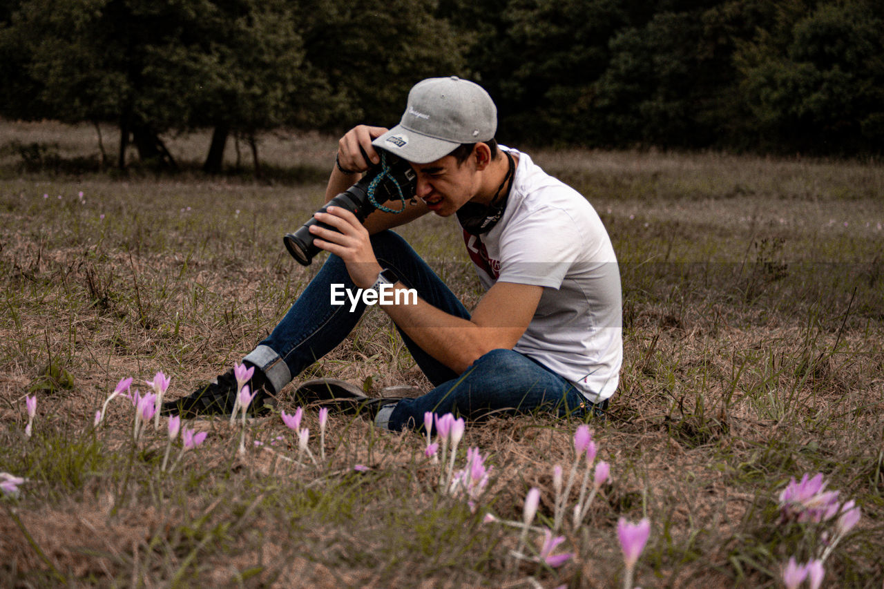 SIDE VIEW OF MAN HOLDING FLOWER IN FIELD