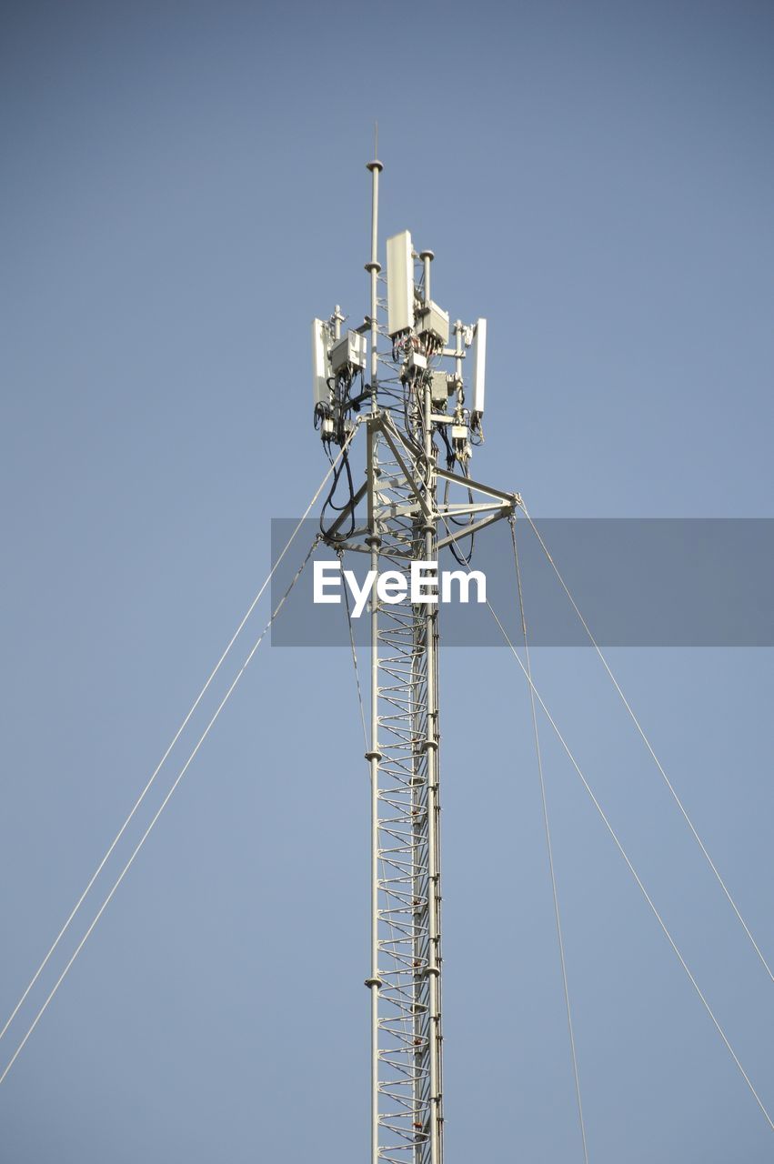 Low angle view of communications tower against clear blue sky