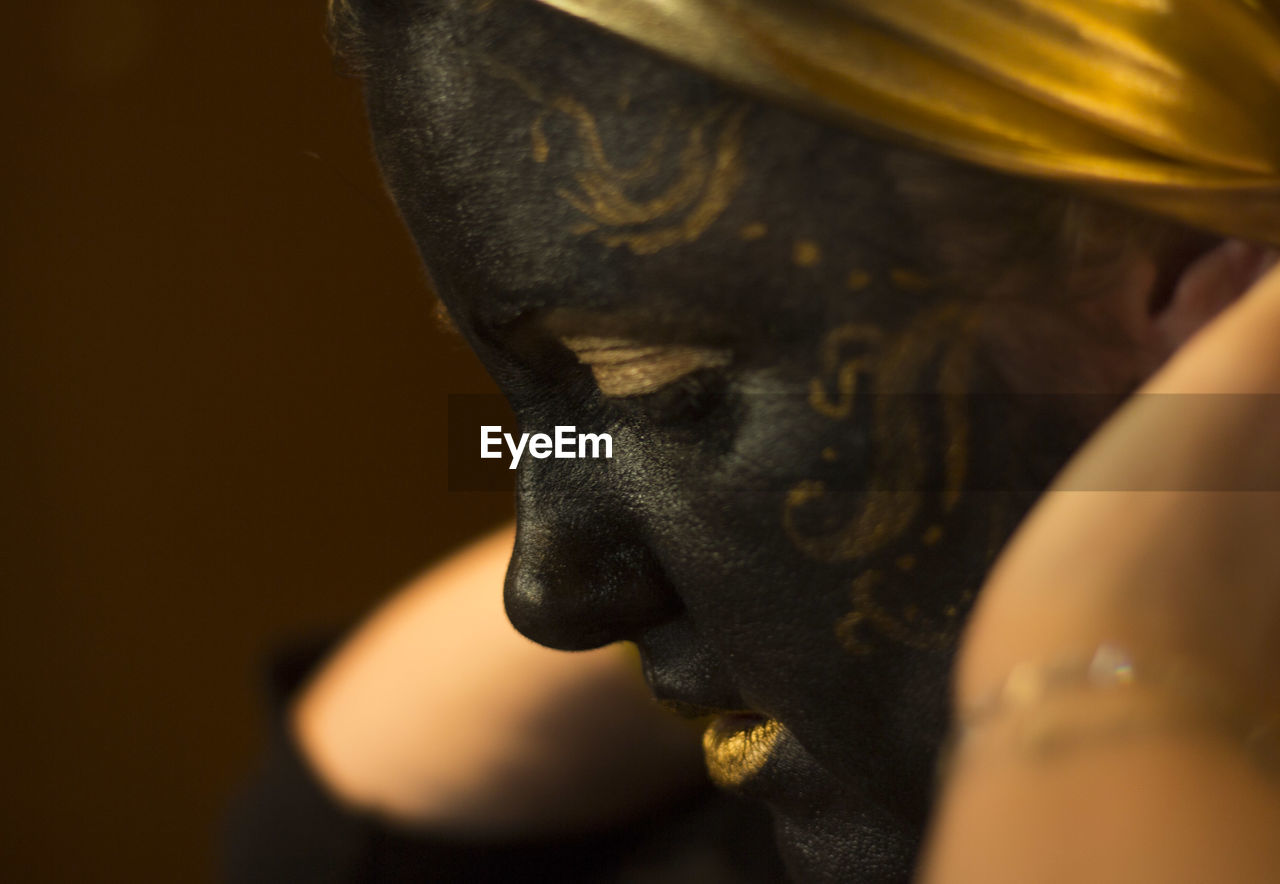 Portrait of a woman with black and gold make up, close up