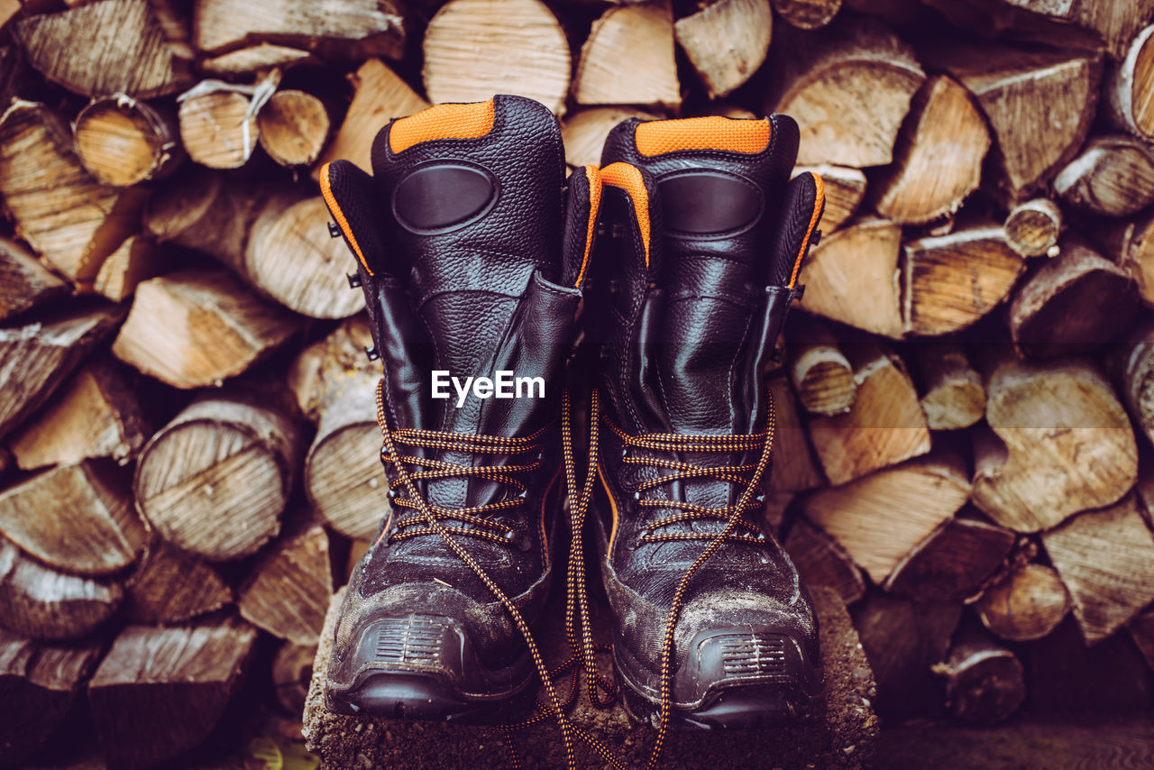 Woodcutter boots and stack of firewood woodcutter equipment and tools hard work outdoor