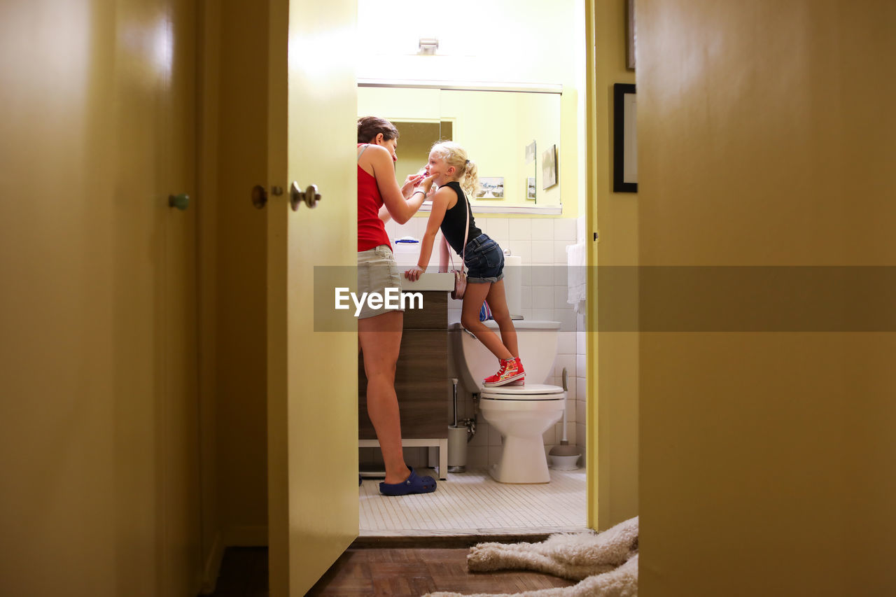 Mom helping daughter brush teeth in small bathroom in new york city