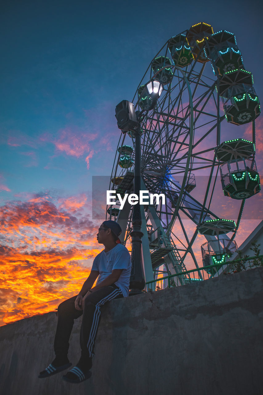 LOW ANGLE VIEW OF FERRIS WHEEL AGAINST SKY DURING SUNSET