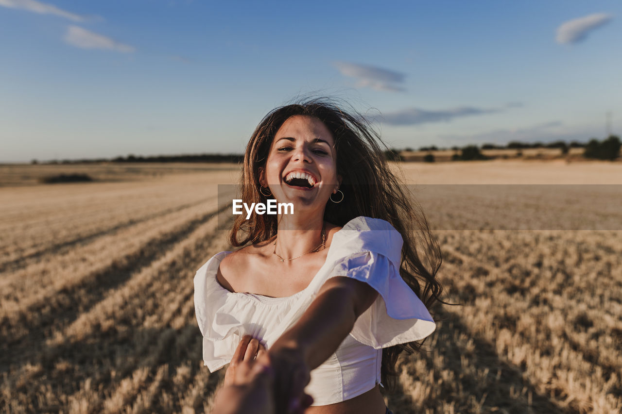 Cropped image of boyfriend holding girlfriend hand on agricultural field