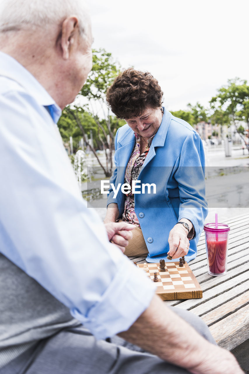 Senior couple sitting on a bench playing chess