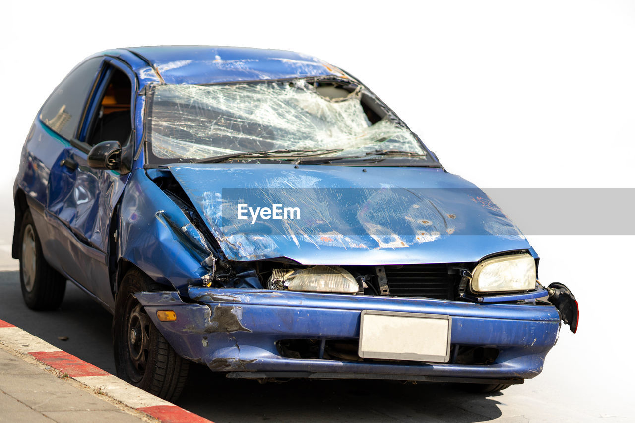 CLOSE-UP OF DAMAGED CAR ON CITY