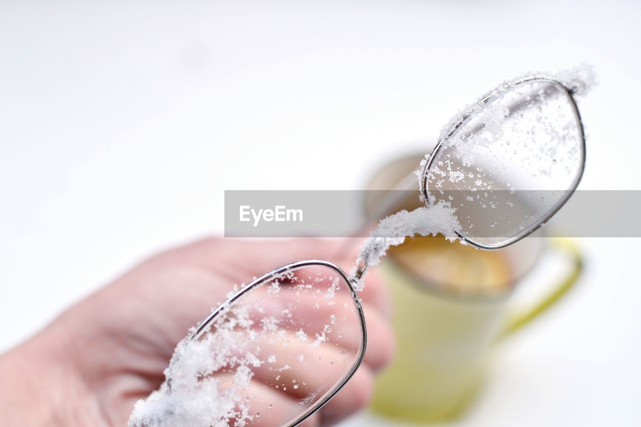 Cropped hand holding snow covered eyeglasses