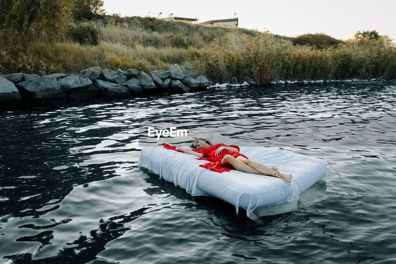 Young woman sleeping on bed in lake