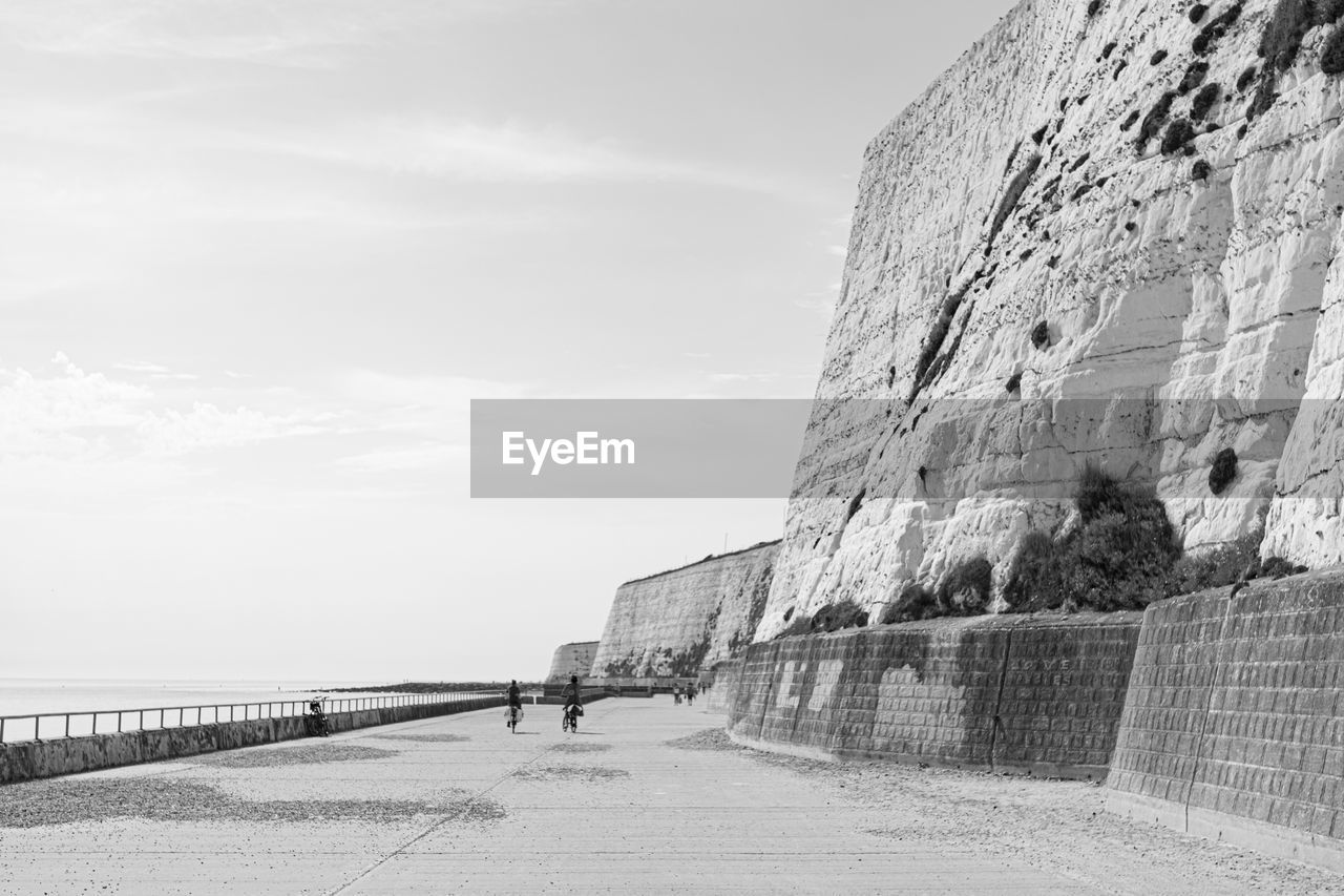 Stone wall by sea against sky