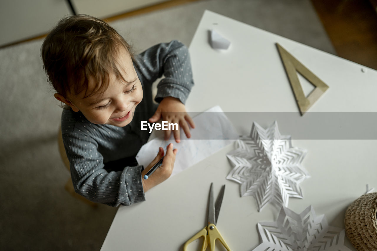Cute boy with pencil and paper drawing at home