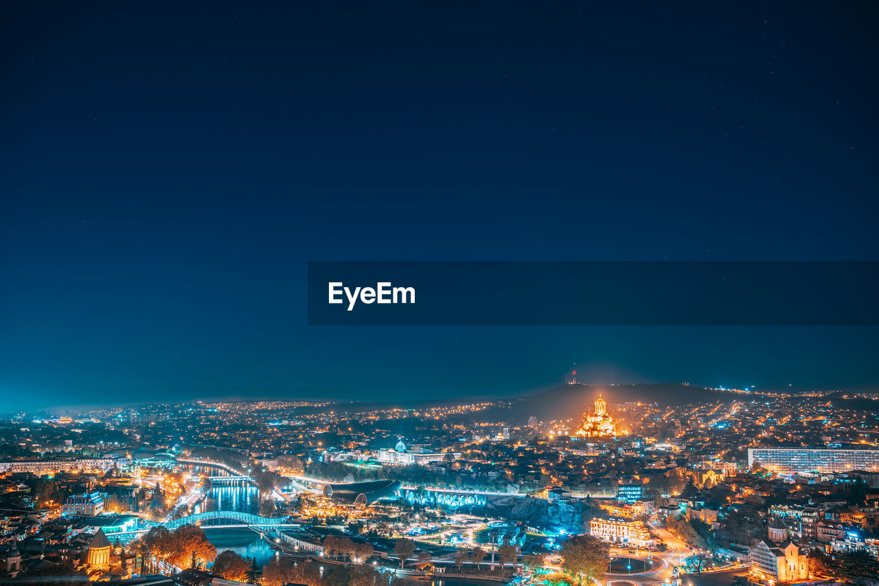 aerial view of illuminated cityscape against sky at night