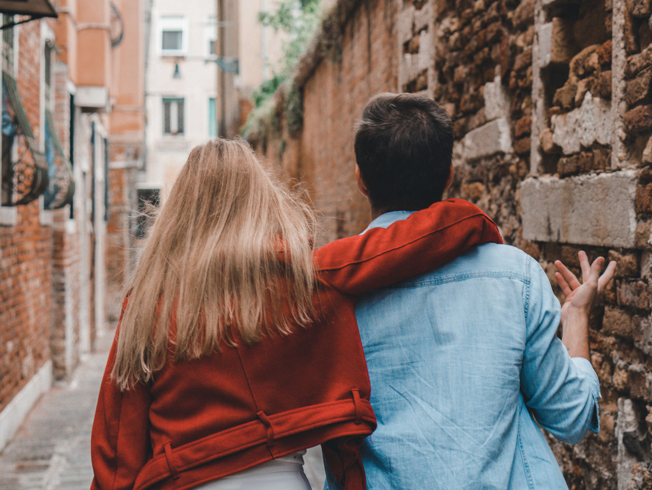 Rear view of couple walking by buildings in city