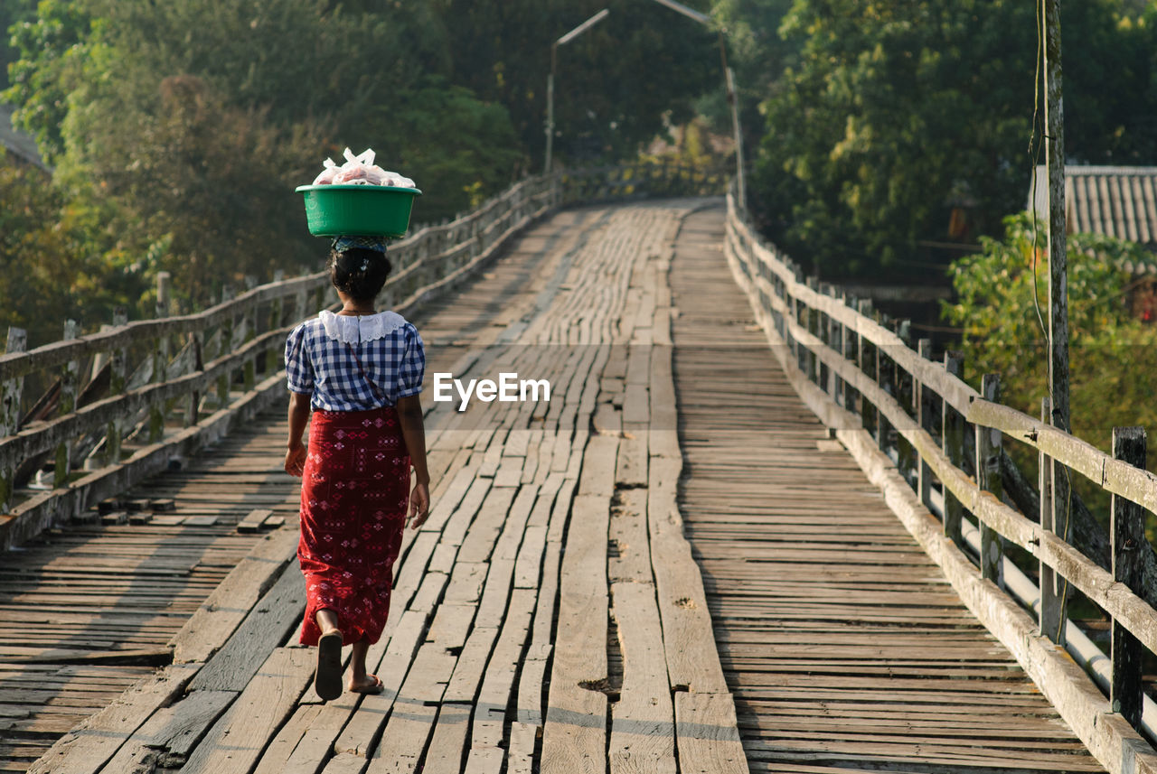 Rear view of woman walking on footbridge