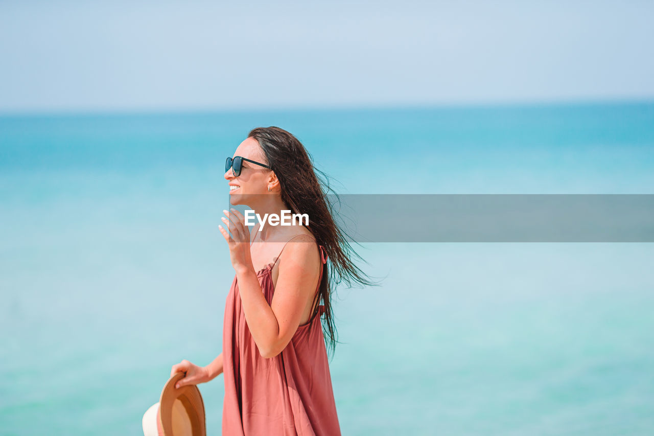 WOMAN WEARING SUNGLASSES AGAINST SEA