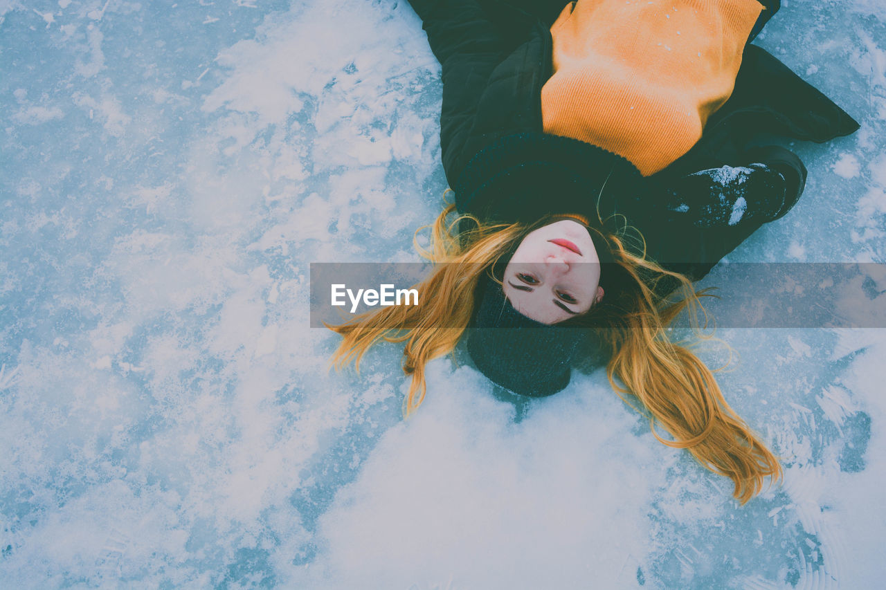 Portrait of young woman lying on snowfield