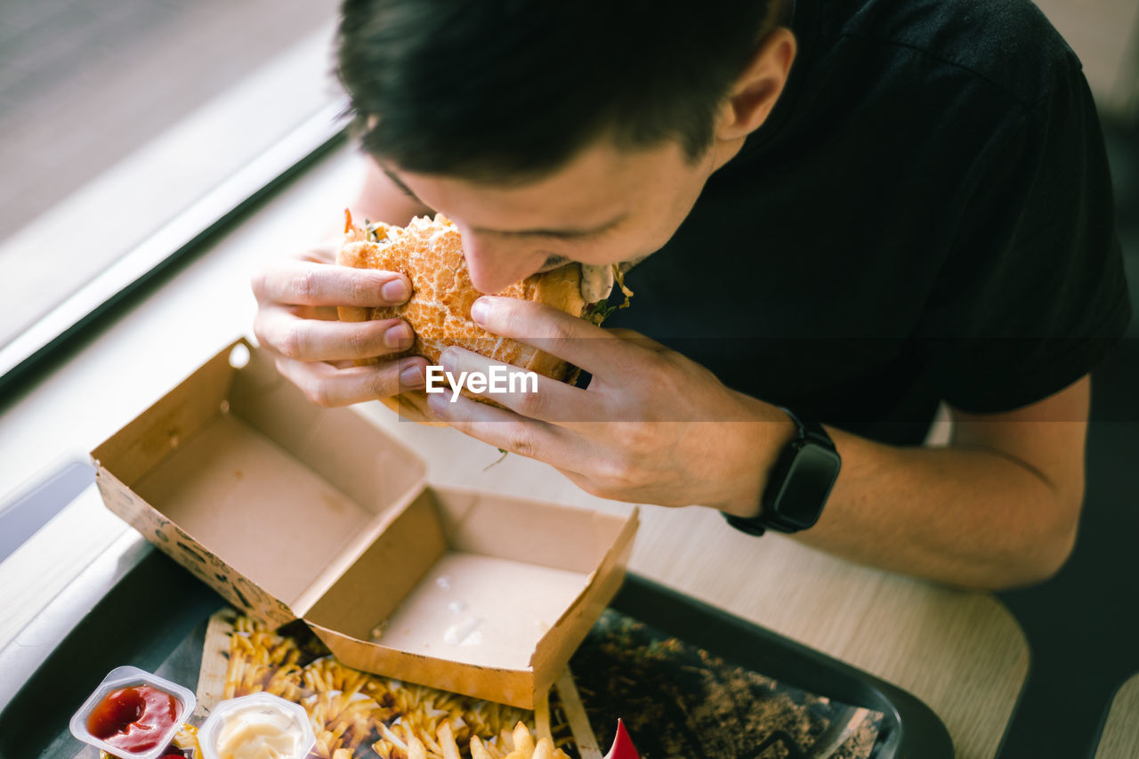 A young man eats fast food at a diner.