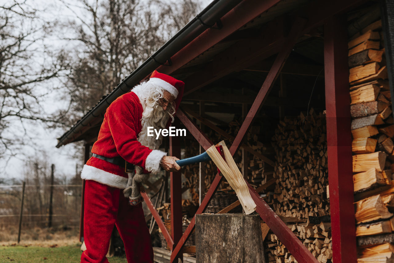 Man wearing santa costume chopping wood