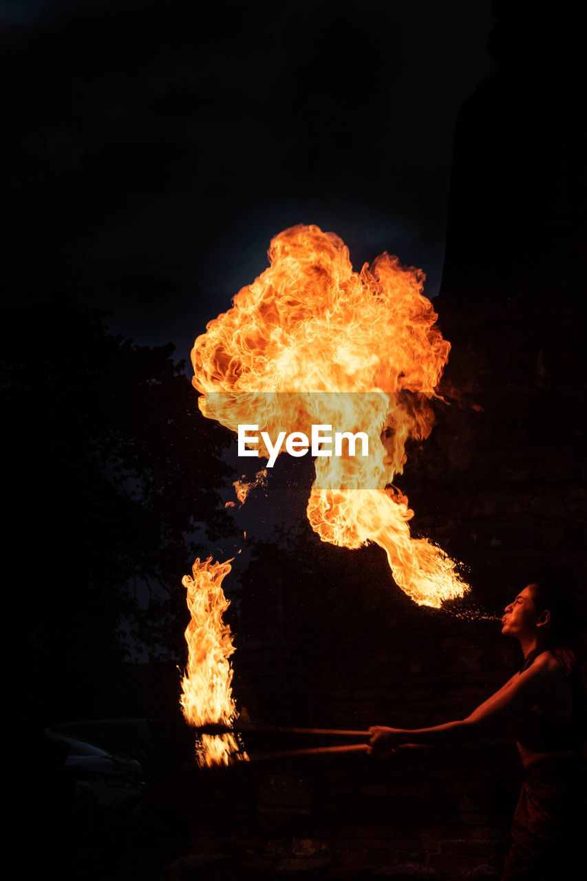 Woman performing breath fire at night