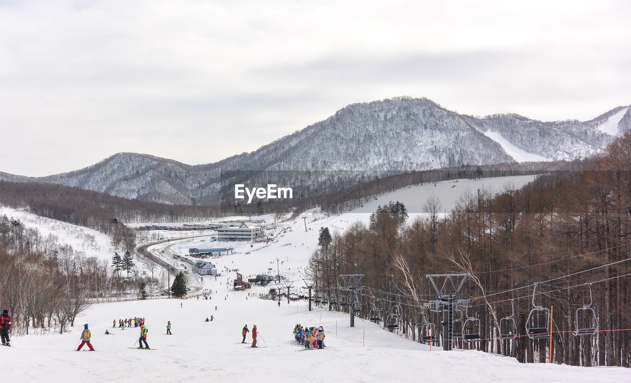 People on snowcapped mountain against sky