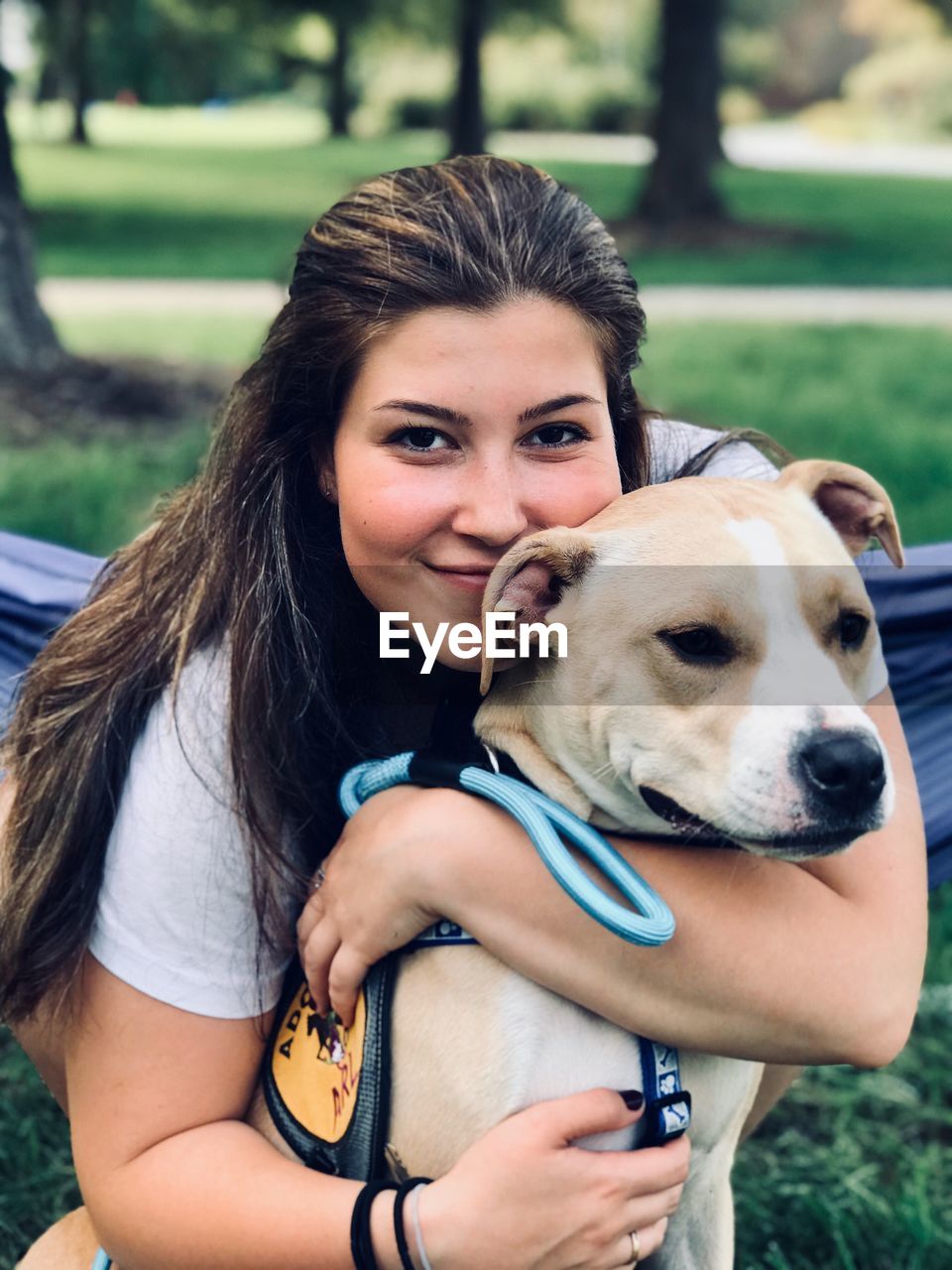 Portrait of smiling woman embracing dog outdoors