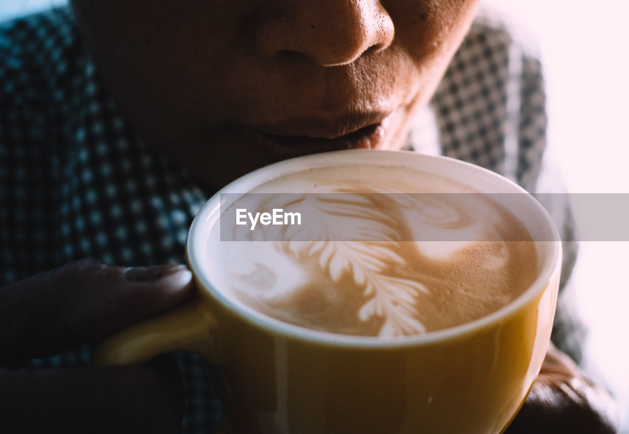 Close-up of woman drinking coffee from cup at cafe