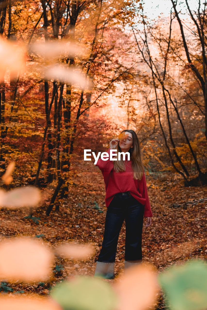 Full length of young woman standing in forest