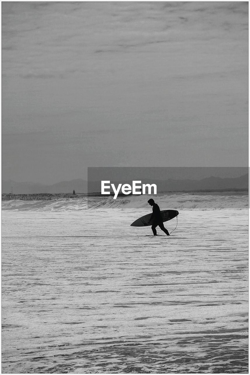 Silhouette surfer walking at beach