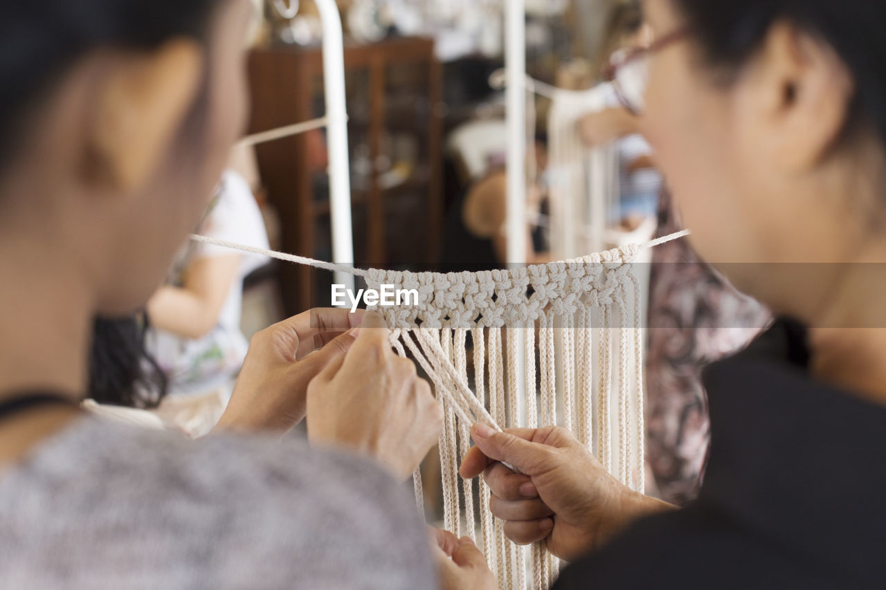 Close-up of women weaving string at workshop