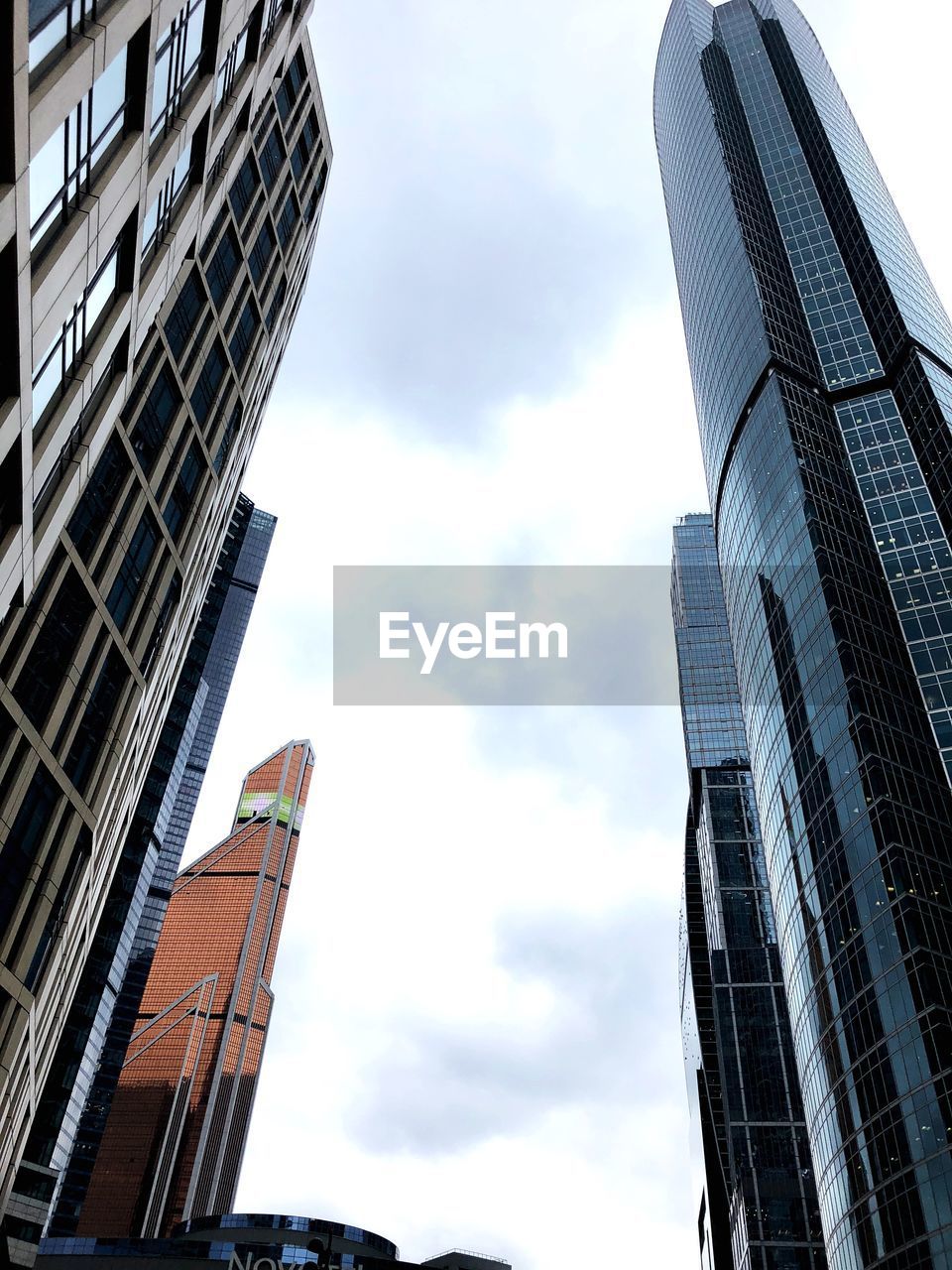 Low angle view of modern buildings in city against cloudy sky 