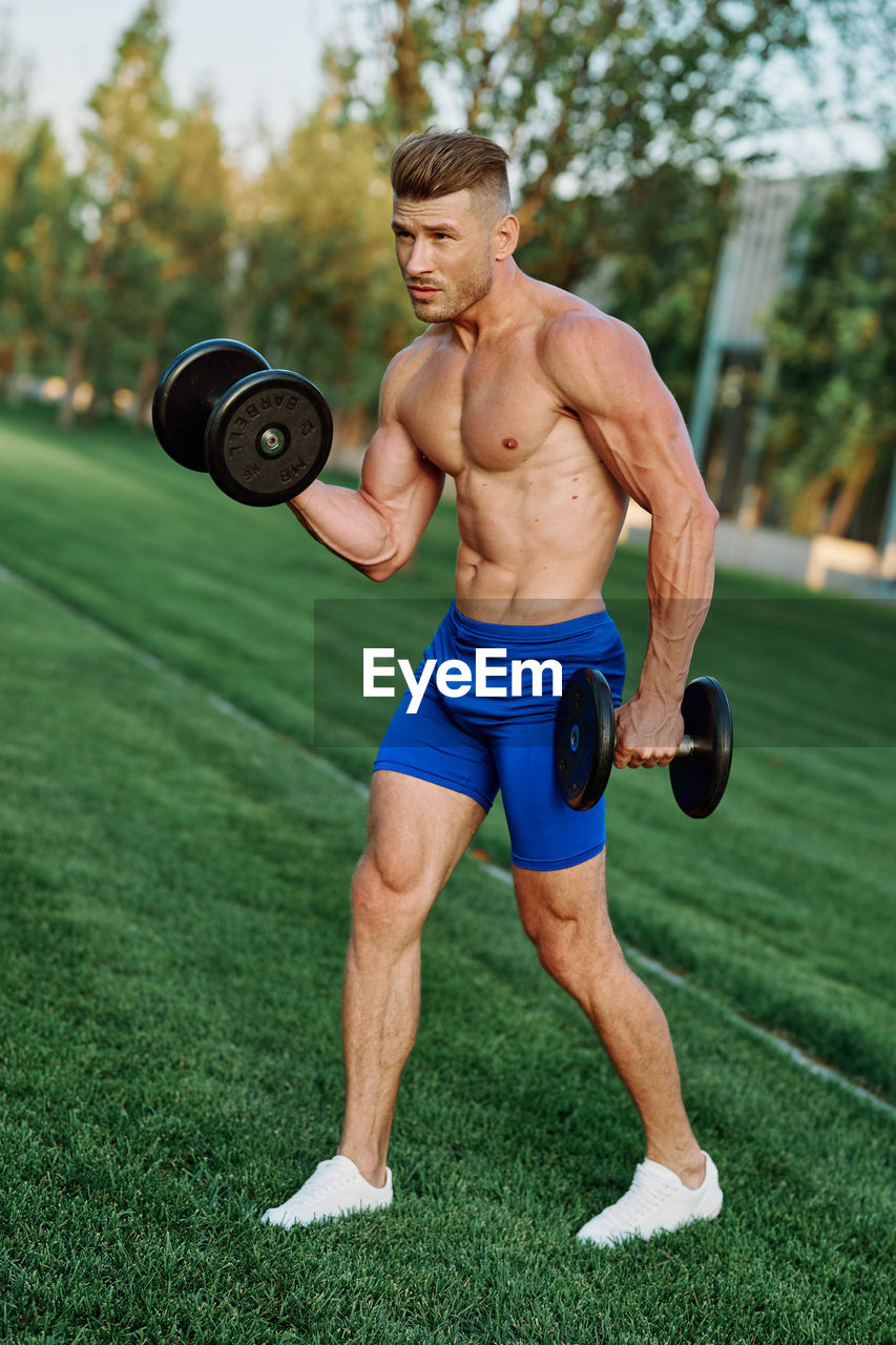 low section of man exercising with dumbbell in gym