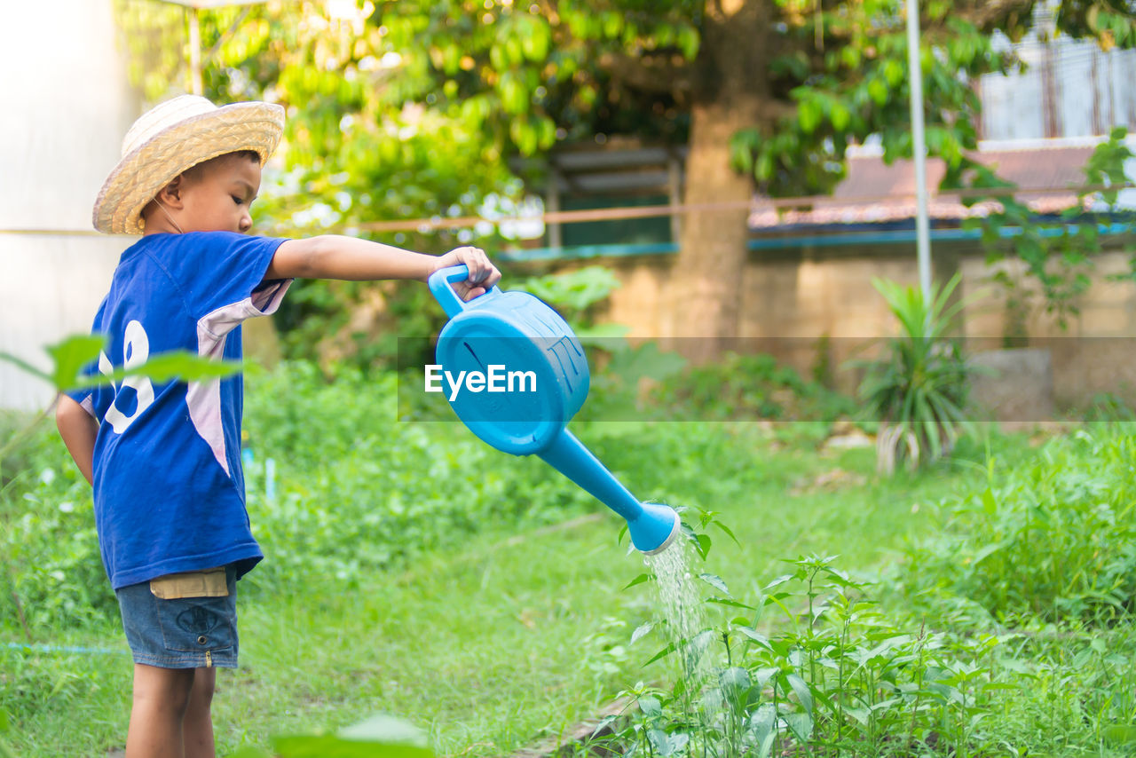 Boy watering plants with can in yard